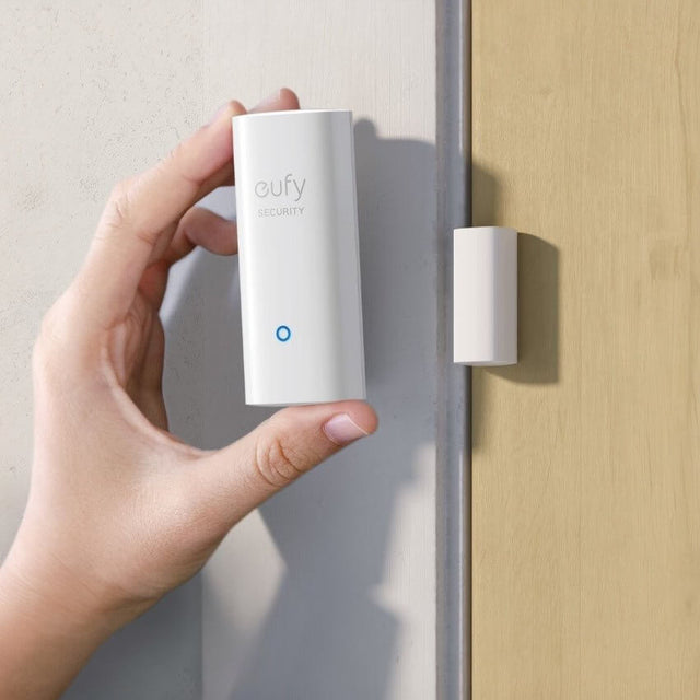 Hand holding eufy Security Smart Entry Sensor next to door frame for easy installation and monitoring.