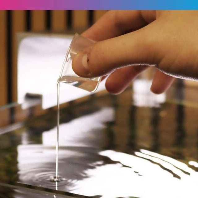 Hand pouring NT Labs Aquarium Cleaner into water to reduce sludge and improve aquarium health.