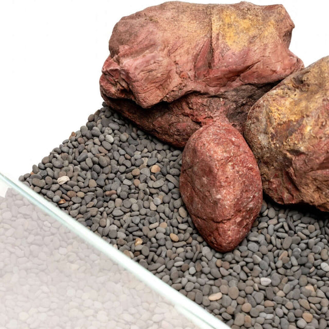 Natural aquarium substrate with smooth gray pebbles and red rocks for aquascaping and terrarium use.