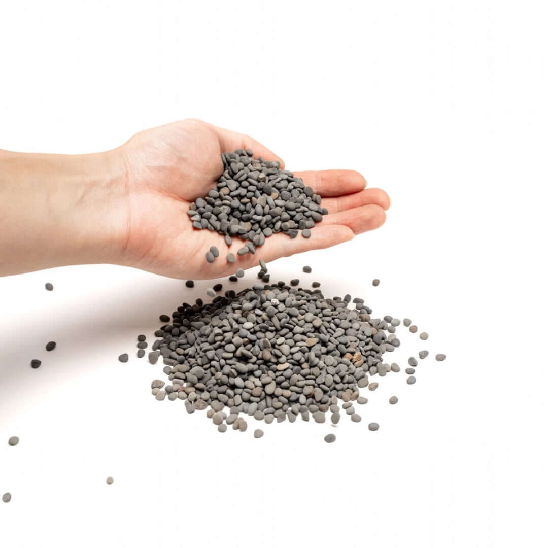 Hand holding UNS Controsand Kona gravel substrate for aquariums and terrariums.
