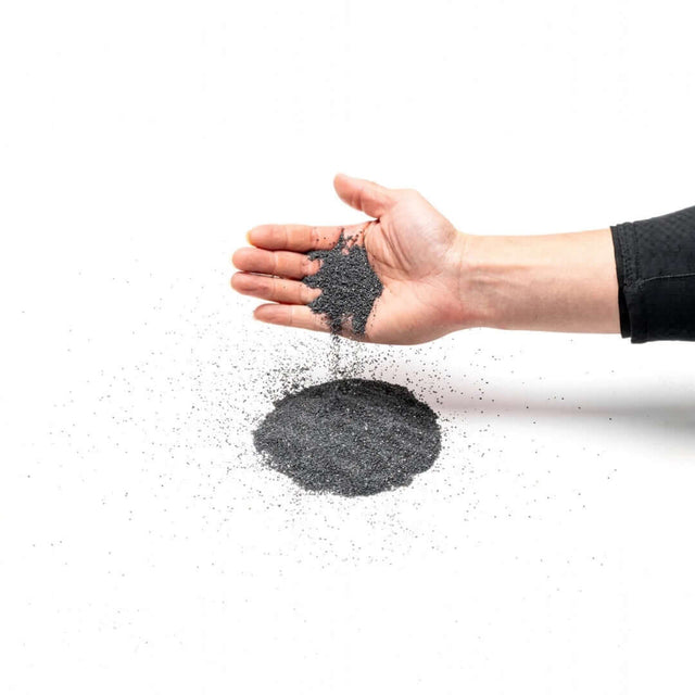 Hand pouring UNS Controsand Maui natural substrate, ideal for aquariums and terrariums, showcasing its fine granules.