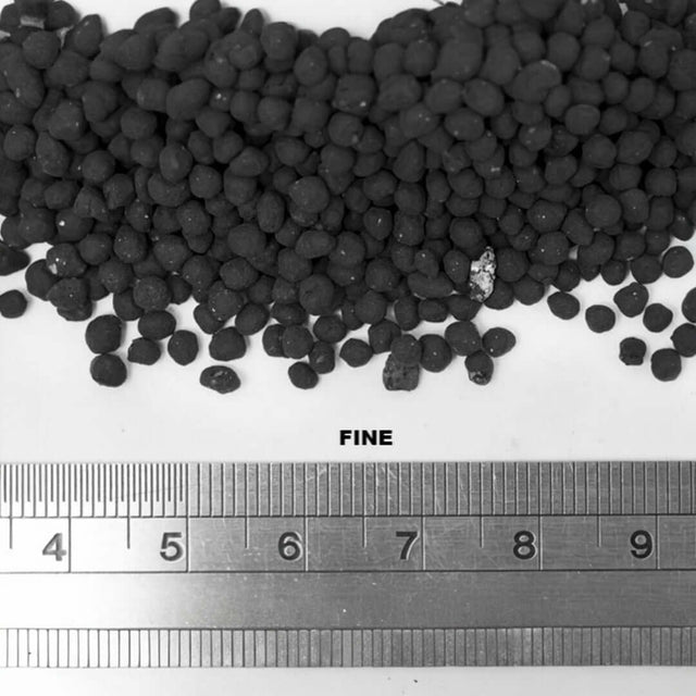 Close-up of UNS Controsoil Black substrate showing fine texture and size comparison with measuring ruler.