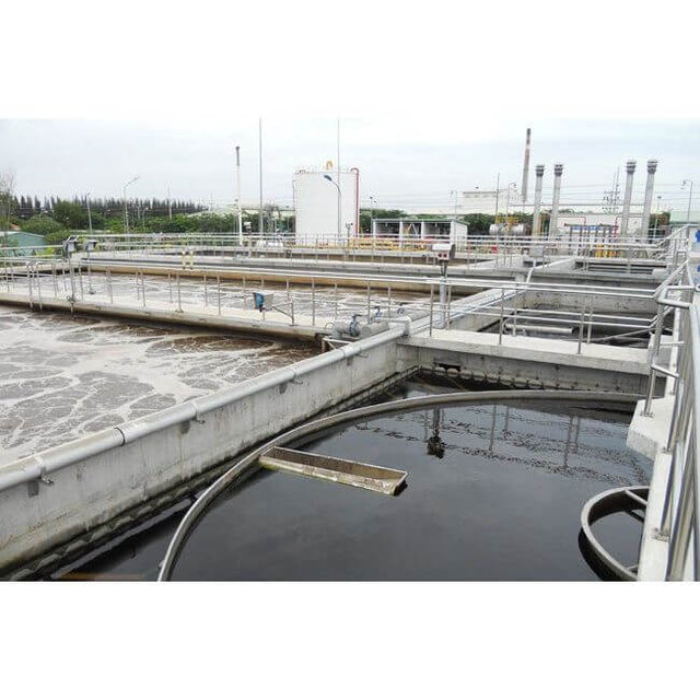 Industrial wastewater treatment facility with tanks and filtration systems under cloudy sky.