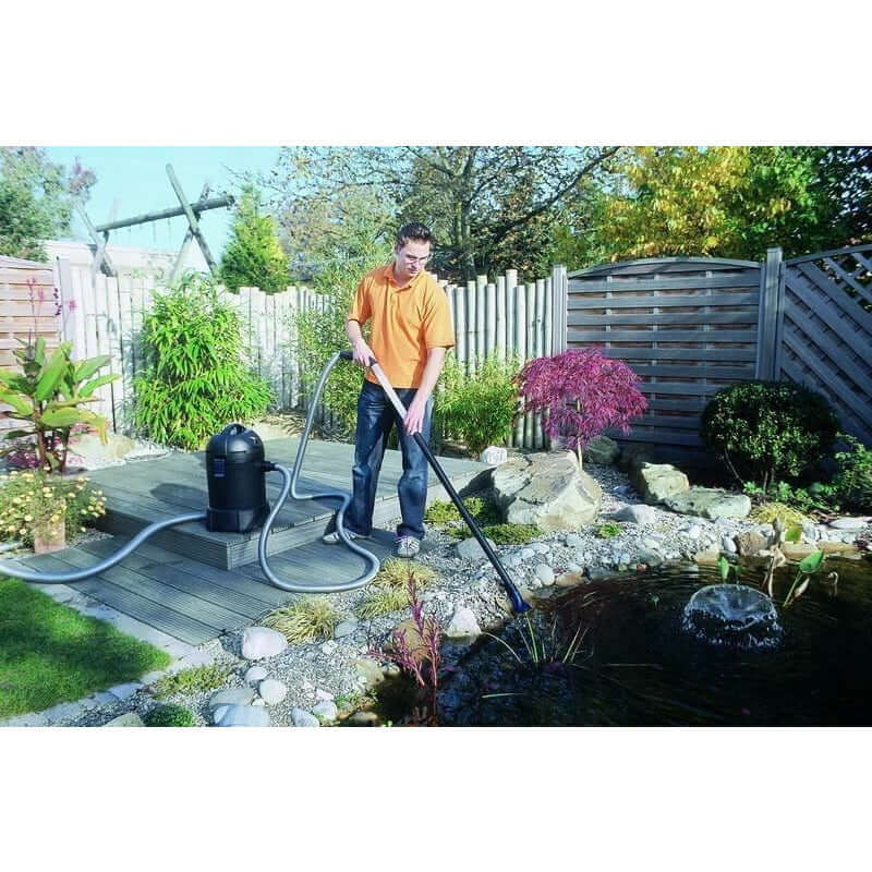 Man using Oase Pondovac Classic Pond Vacuum Cleaner to clean a garden pond, showcasing effective pond maintenance.