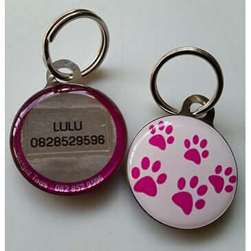 Pet ID tag featuring pink paw prints and contact information for lost pets. Fun and functional design for pet safety.