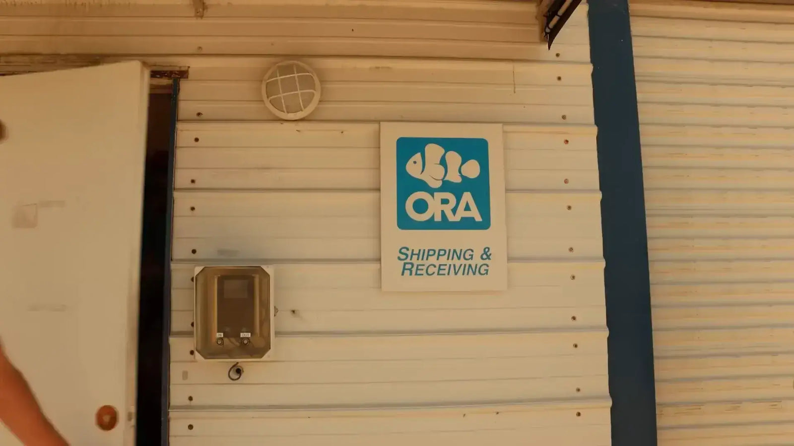 ORA Farms Shipping and Receiving entrance sign on a building, showcasing marine aquaculture innovation.