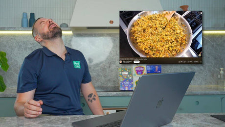 Nutritionist reacting humorously to a home cooked dog food recipe video in a modern kitchen.