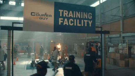 The Courier Guy training facility interior with workers, training equipment, and signage clearly visible.