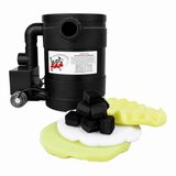 A black cylindrical motorized brush cleaner with a side-mounted pump and a visible product label, shown on a white background with several black brush heads and yellow-green foam pads in front.