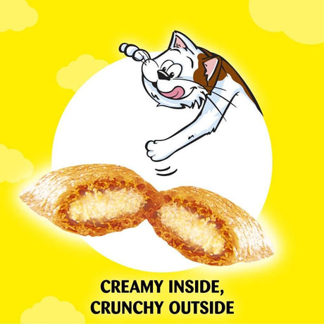 Cat excitedly reaching for Dreamies Cat Treats with a creamy inside and crunchy outside, against a bright yellow background.