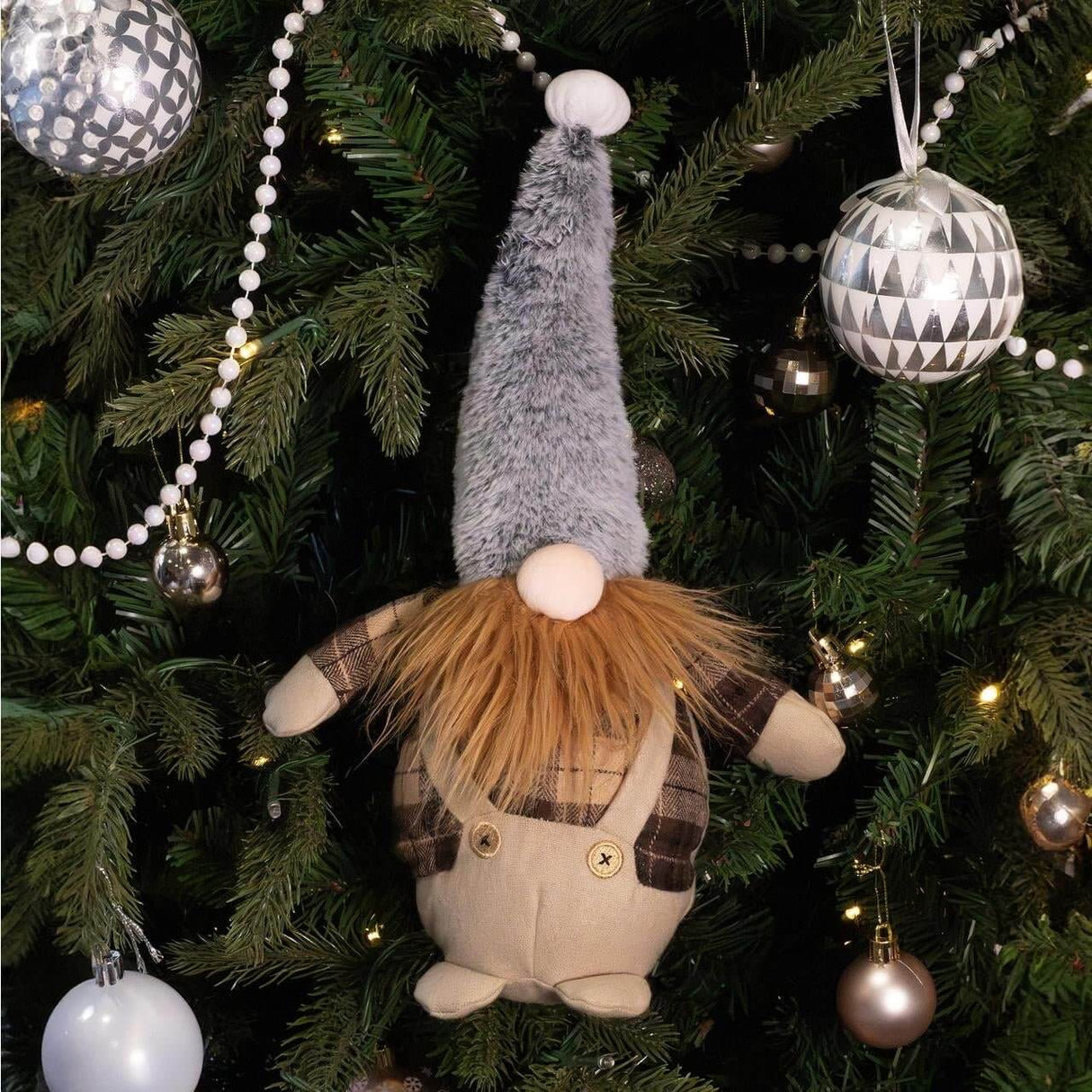 Gerard Gonk holiday dog toy hanging on a Christmas tree, featuring plaid shirt, overalls, and a tall gray hat.