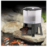 Grech Solar Auto Pond Fish Feeder dispensing fish food into a pond with colorful koi fish.