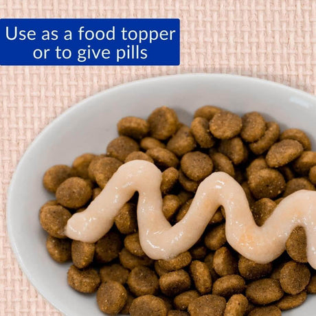 Churu hairball control cat treat on kibble, shown as a food topper or for administering pills.