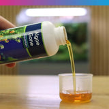 Bottle of NT Labs Algae Gone being poured into a measuring cup for aquarium algae treatment.