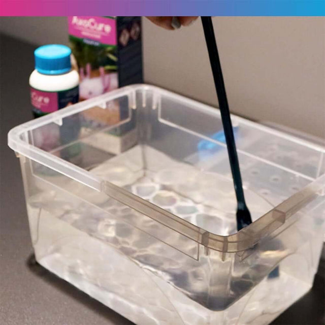 Person mixing NT Labs AxoCure medicine in a clear container for axolotl treatment.