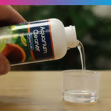 NT Labs Aquarium Cleaner 100ml being poured into a measuring cup, suitable for tropical and coldwater aquariums.