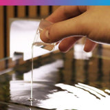 Hand pouring NT Labs Aquarium Cleaner into water to reduce sludge and improve aquarium health.