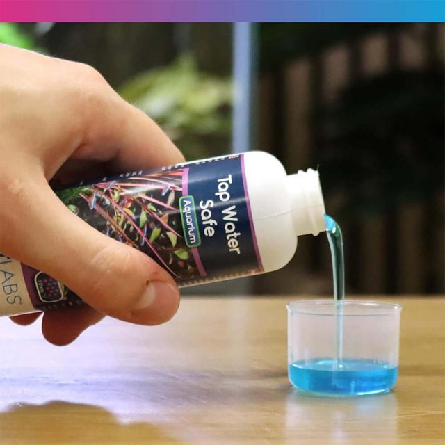 Hand pouring NT Labs Aquarium Tap Water Safe into a measuring cup, showcasing its vibrant blue color.
