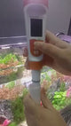 Person using Hygger Water Quality Meter near an aquarium to measure water quality parameters.