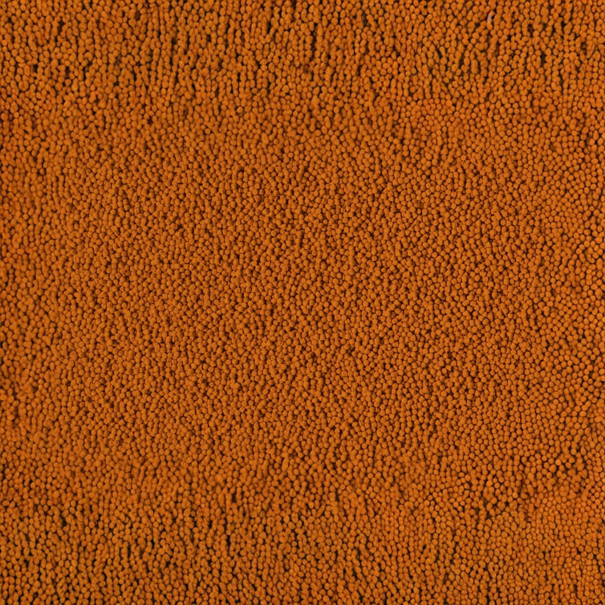 Close-up of Tetra Cichlid Colour Pellets showcasing vibrant orange color and fine texture, ideal for cichlid nutrition.