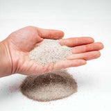 Hand holding UNS Controsand natural substrate for aquariums, showcasing its fine granule texture.
