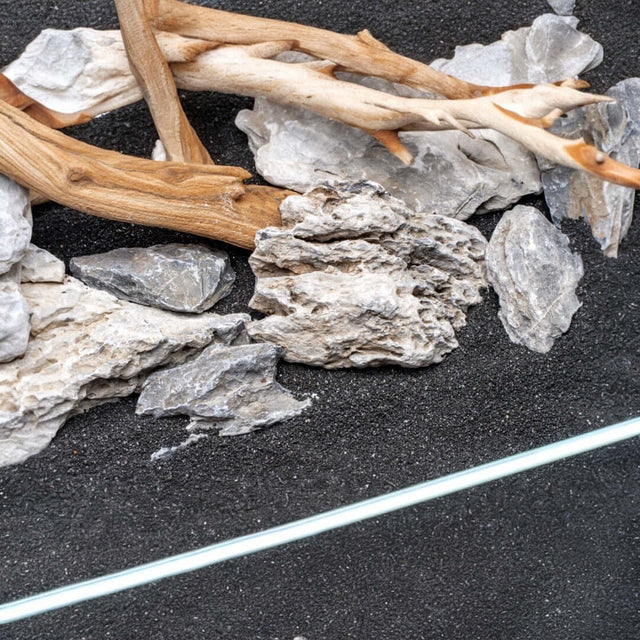 Natural substrate blend of controsand, driftwood, and rocks for aquariums and terrariums.