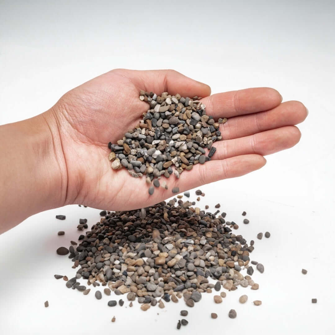 Hand holding UNS Controsand for aquariums, showcasing natural substrate for freshwater environments.