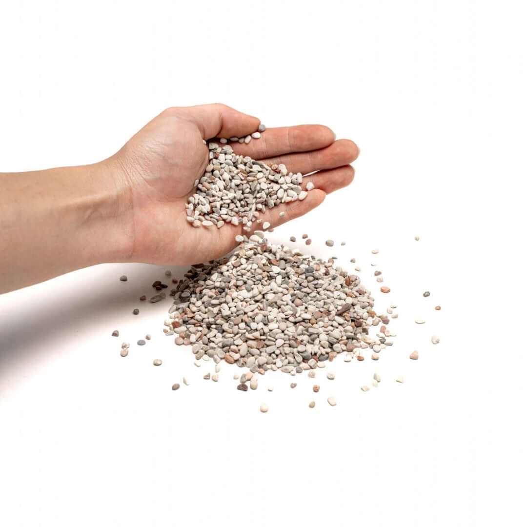 Hand holding UNS Controsand Tahoe natural substrate for aquariums and terrariums, showcasing various granules.
