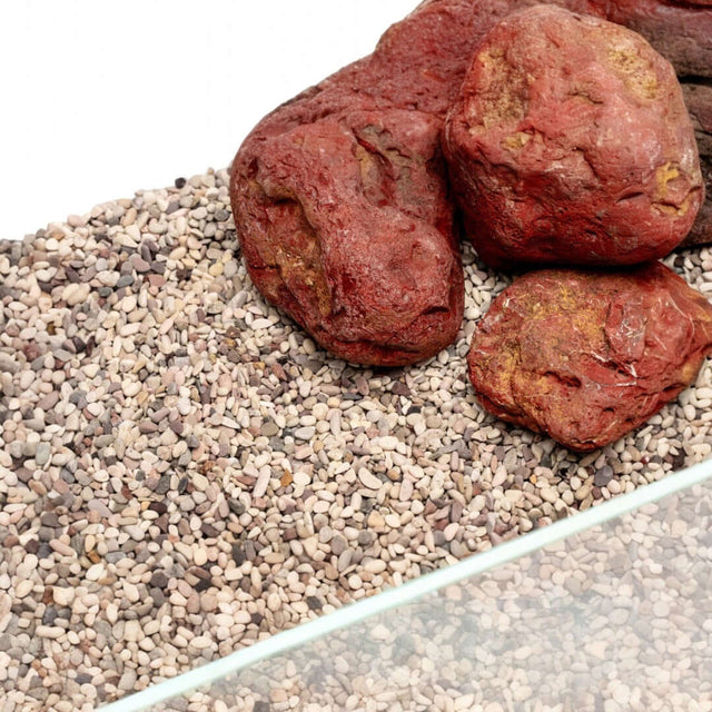 Natural substrate UNS Controsand Tahoe for aquariums, featuring granules and decorative red rocks.