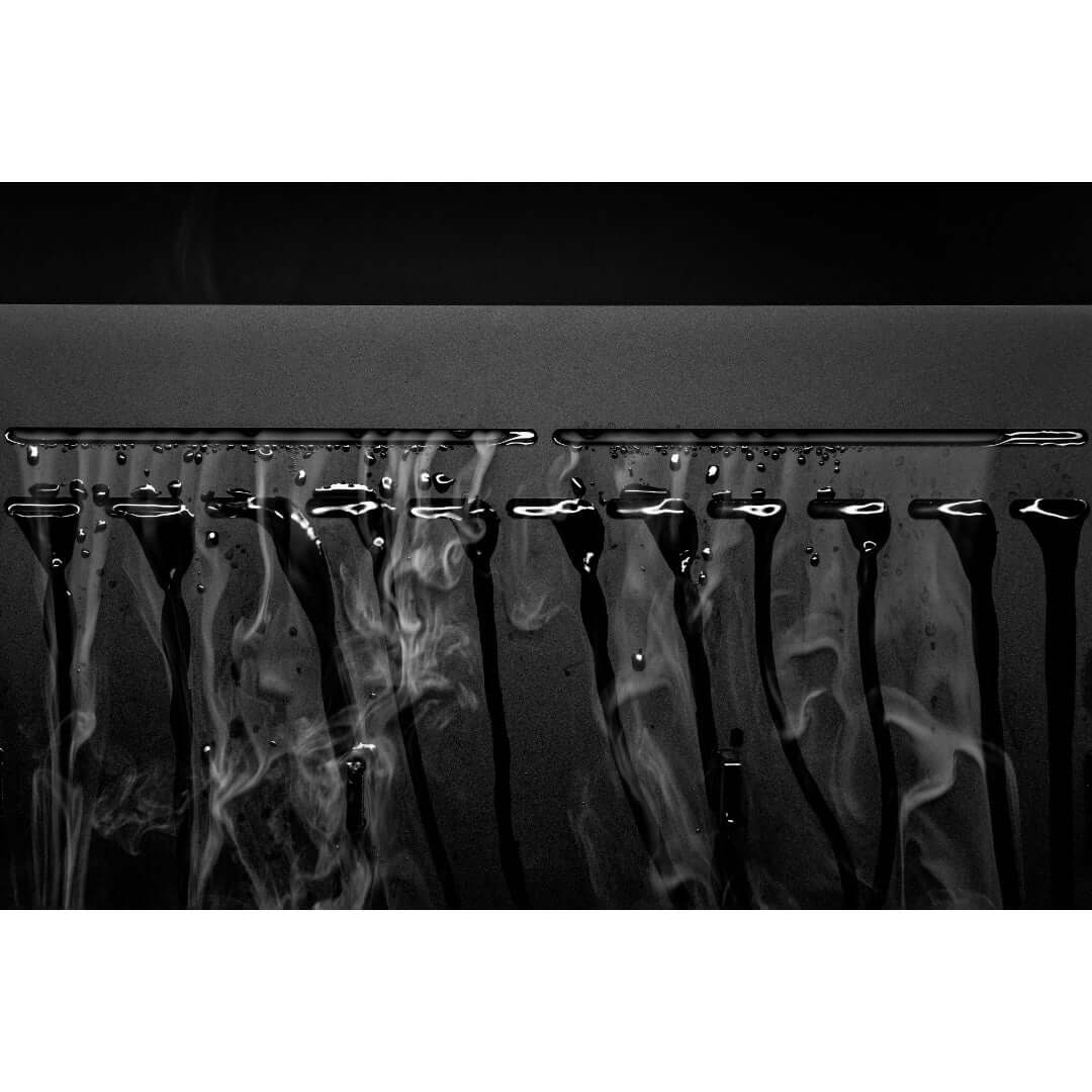 Close-up of smooth black surface with water droplets and vapor, showcasing condensation effects.