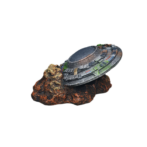 Crashed UFO aquarium ornament on rocky base, perfect for adding an extraterrestrial touch to aquariums.